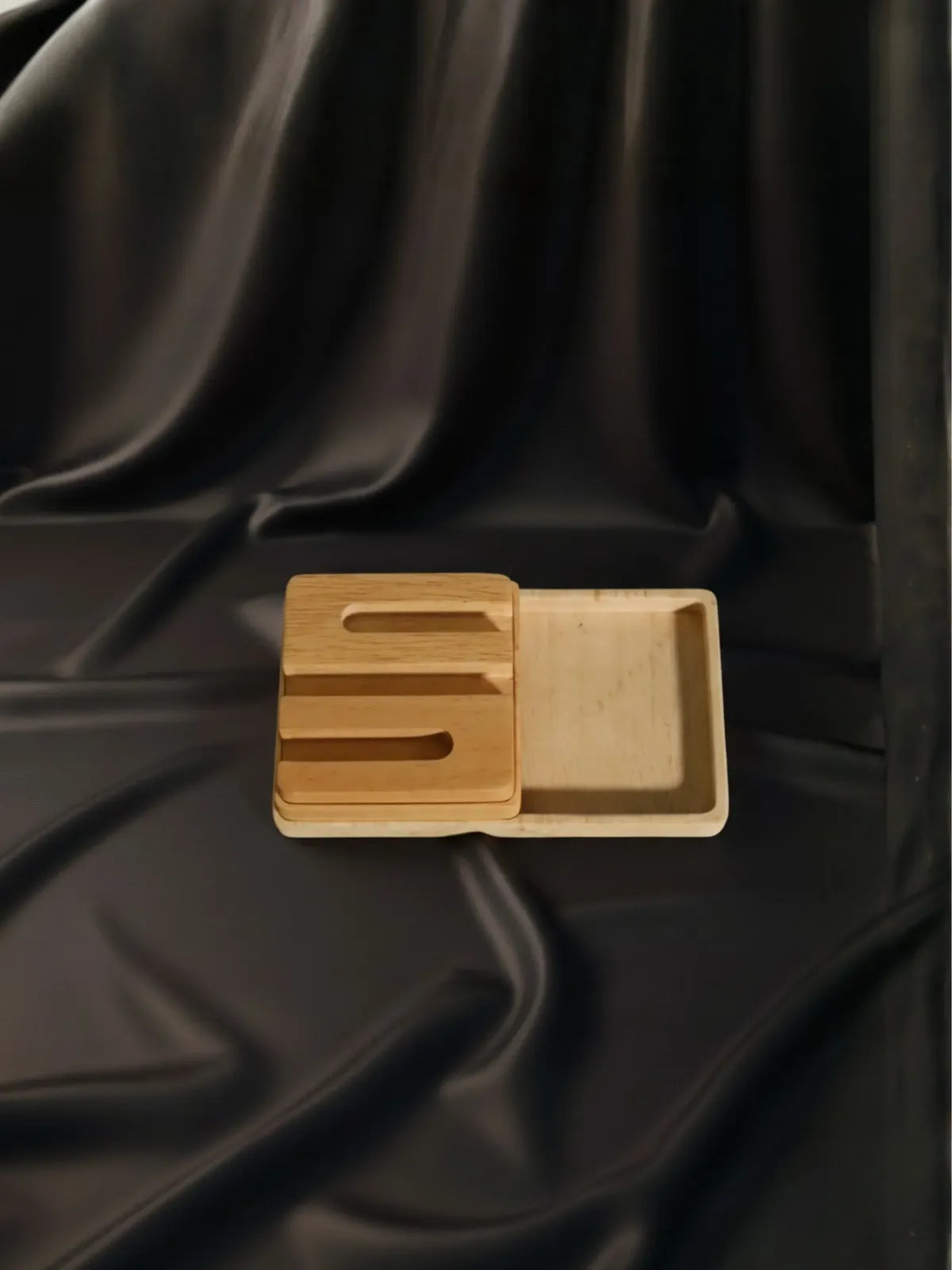 Wooden tray with a lid on a black fabric background