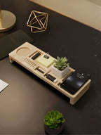 Wooden desk organizer with phone, stationery, and small plant on a dark surface.