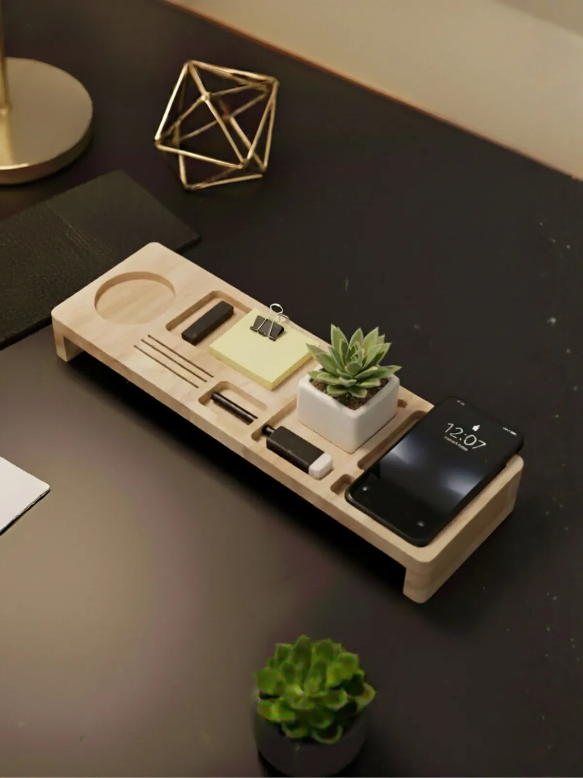Wooden desk organizer with phone, stationery, and small plant on a dark surface.