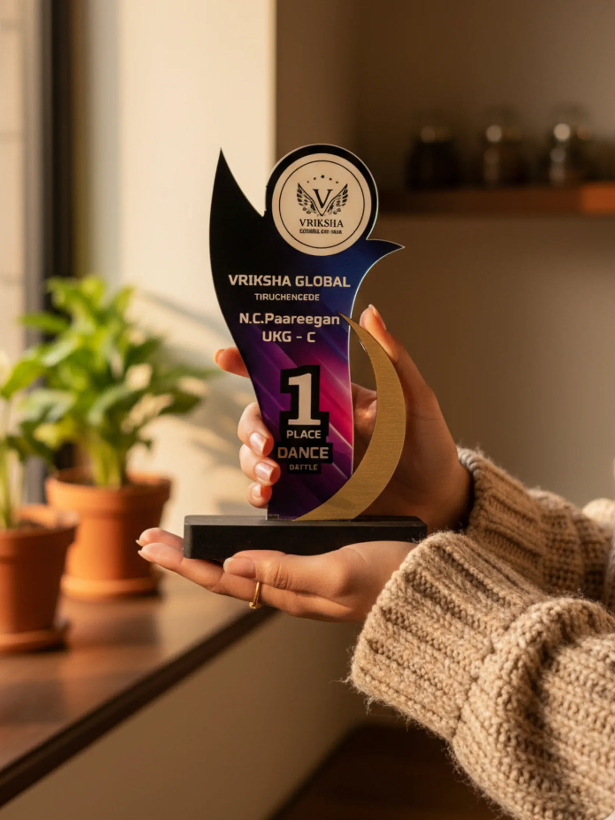Person holding a Vriksha Global award in a home setting with plants in the background