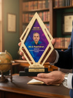 Person holding a diamond-shaped award with a portrait and text on a bookshelf background