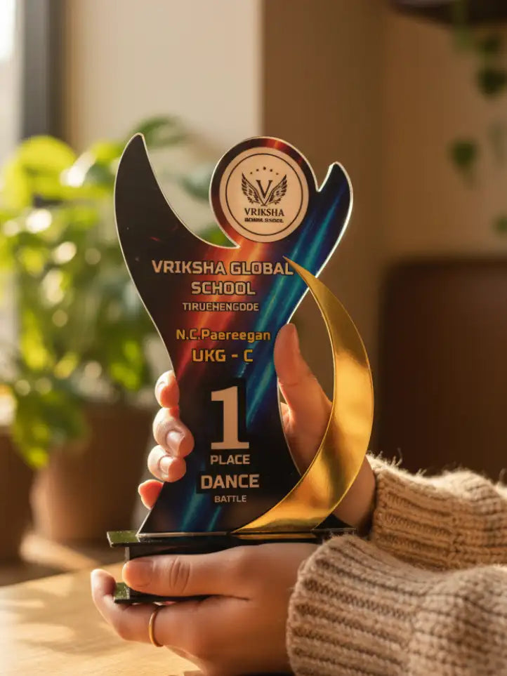 Person holding a trophy with 'Vriksha Global School' on it, indoors.