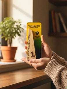Person holding a yellow and green certificate on a wooden surface with a plant in the background