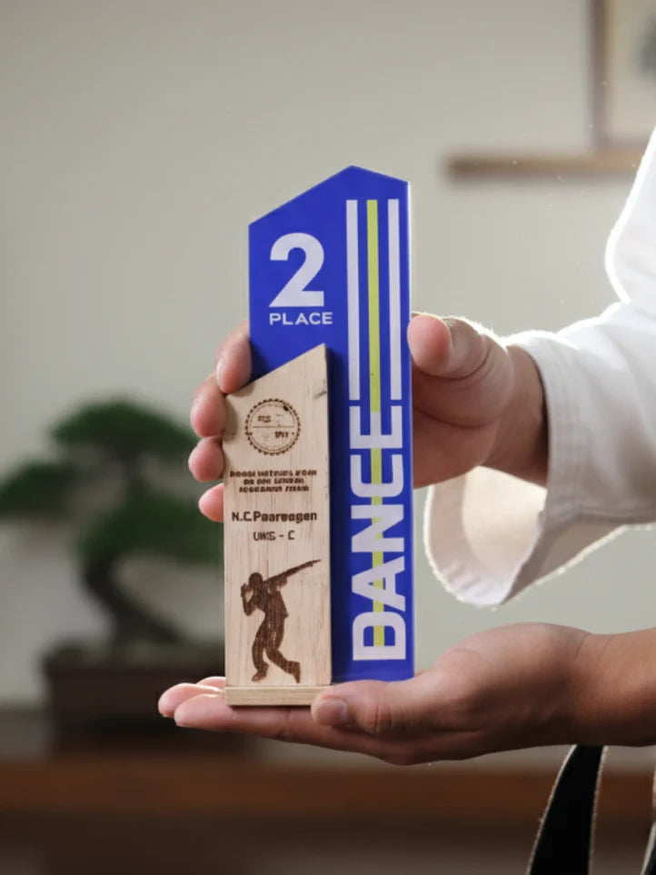 Hand holding a blue and wooden trophy with 'Bange' branding