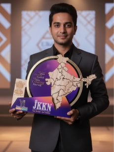 Man in a black suit holding an award with 'JKKN' on a blurred background