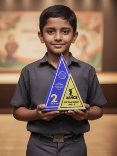 Young boy holding a blue and yellow award in front of a blurred background