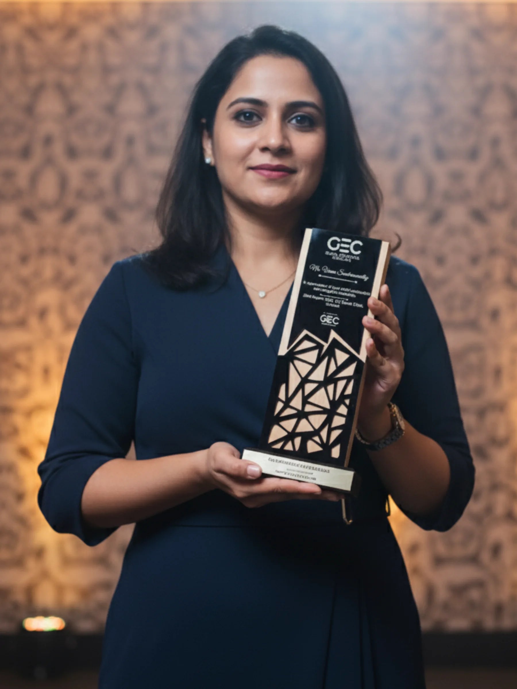 Woman holding an award with a geometric design against a warm-toned background
