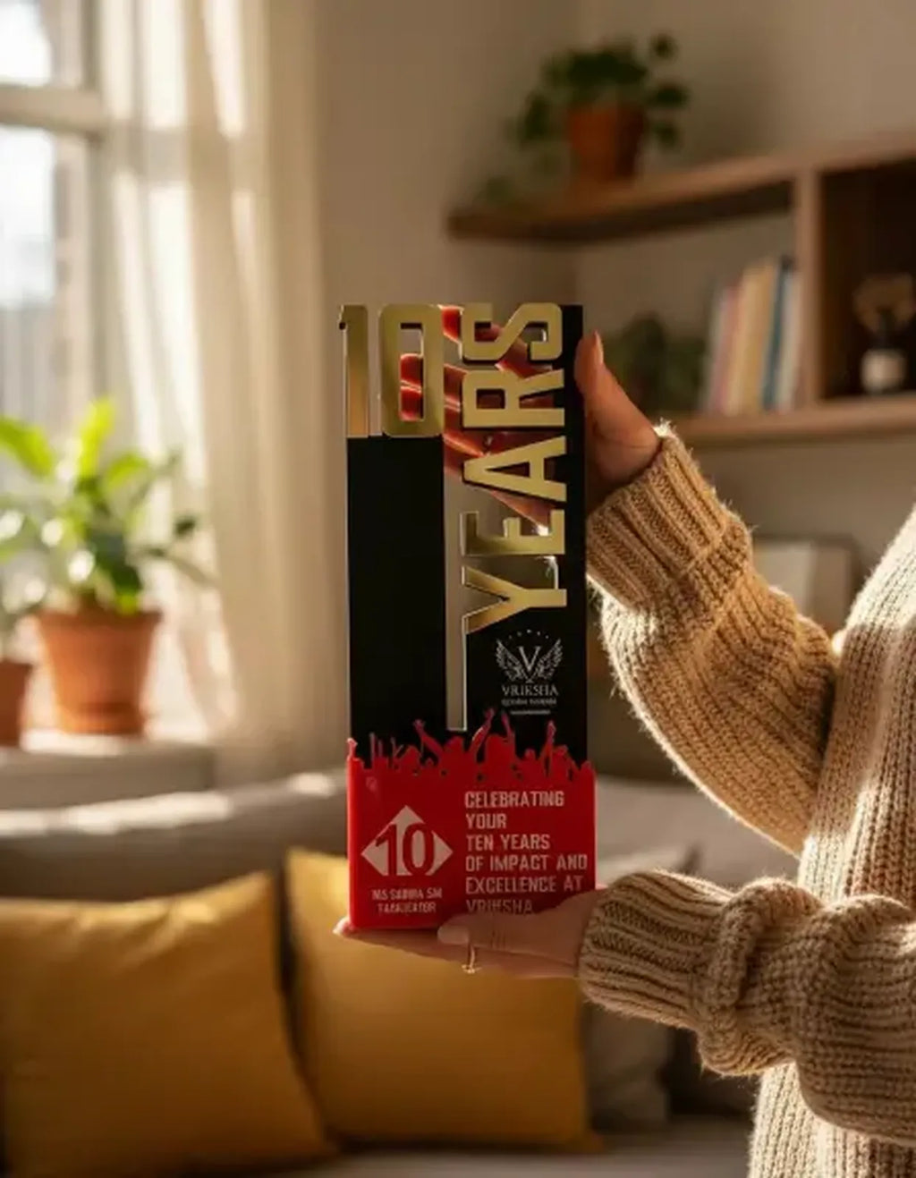 Person holding a '10 Years' celebration box in a cozy indoor setting