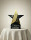 Star-shaped award with engraved text on a white surface