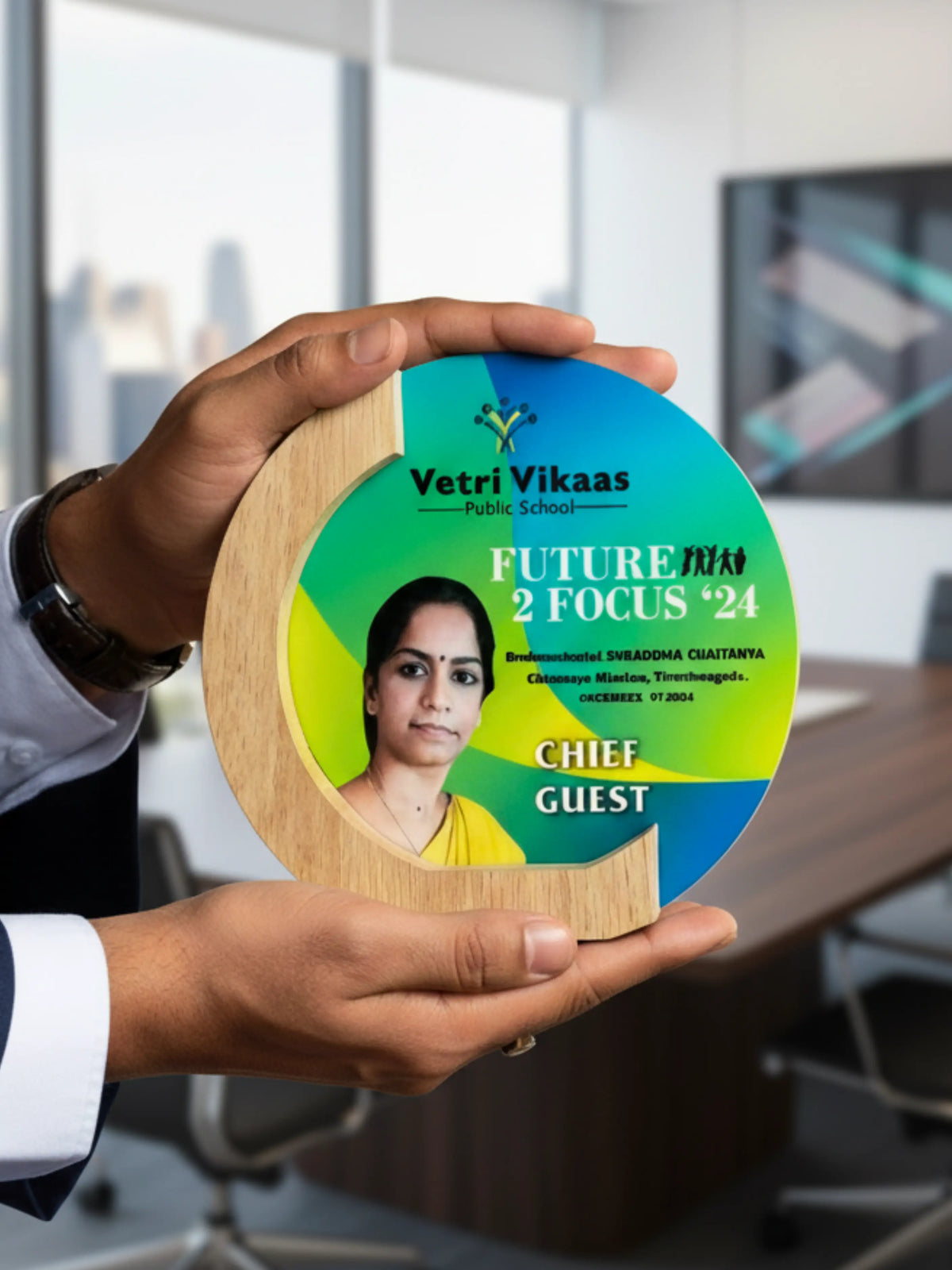Person holding a round wooden plaque with a photo of a woman and text in an indoor setting.